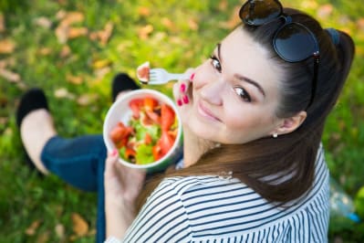 Student sitting on the grass eating salad